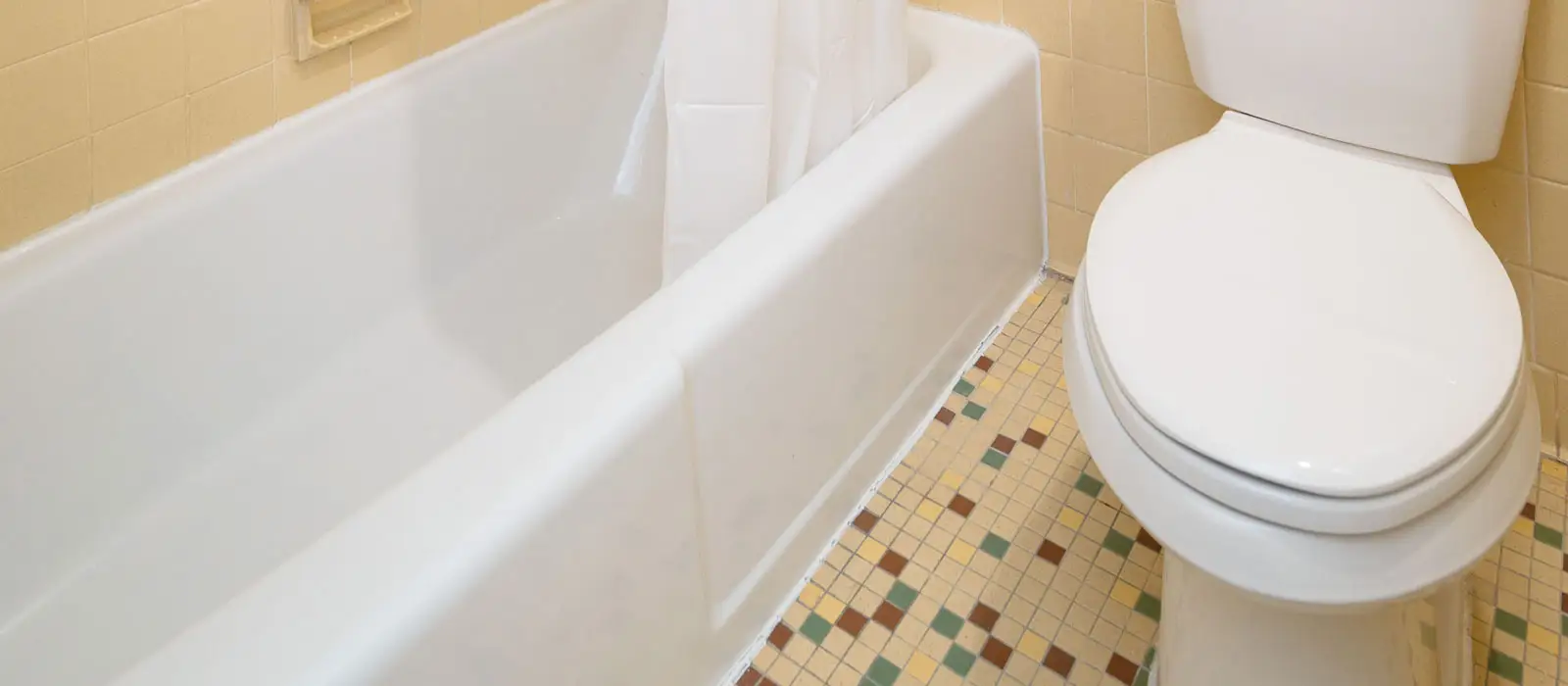 A white bathtub with a shower curtain and a white toilet on a tiled floor
