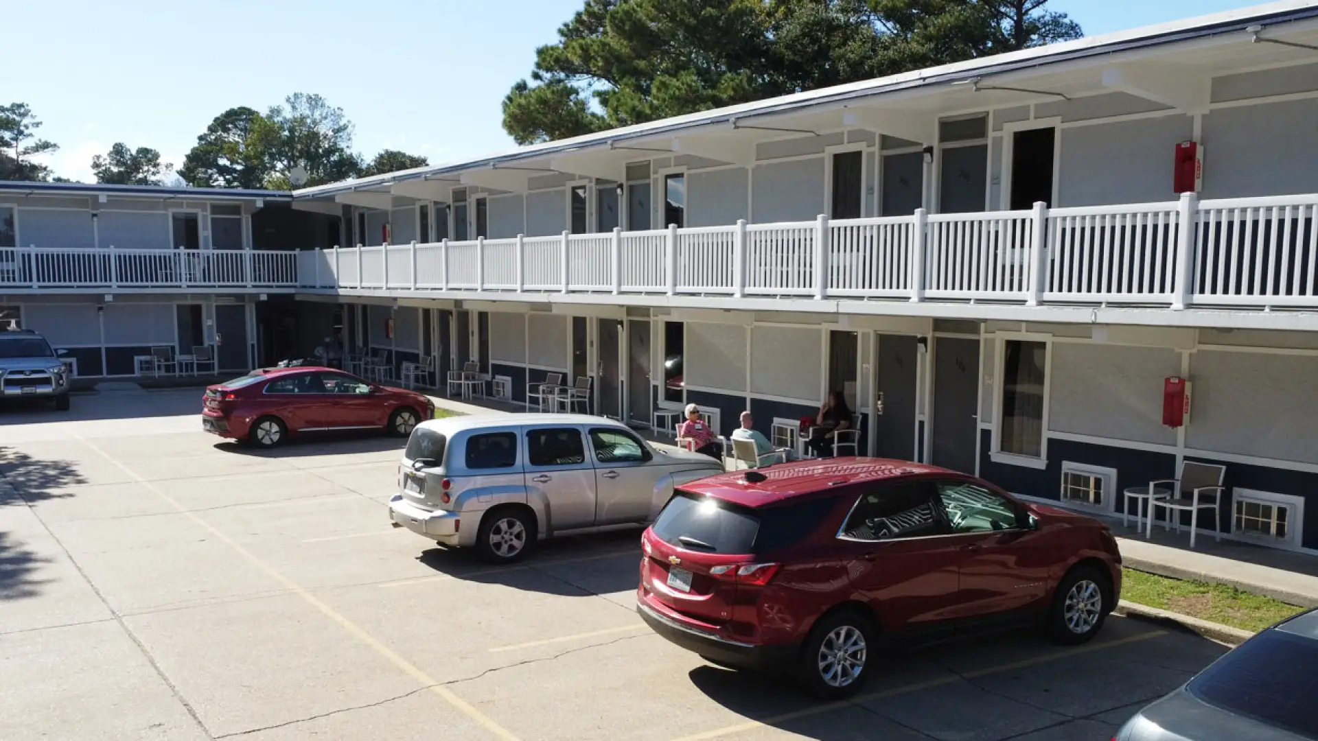 The Heart of Manteo Motor Lodge exterior, a two-storey motor lodge with white railings and parking in front
