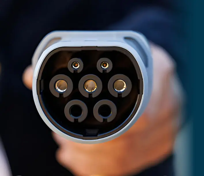 A driver connecting a charging cable to an electric vehicle