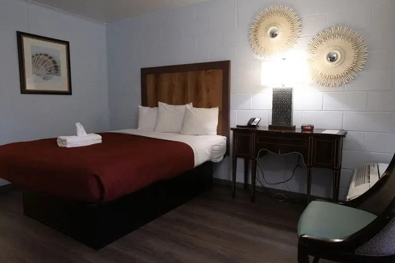 One bed with white linens in a Heart of Manteo guest room
